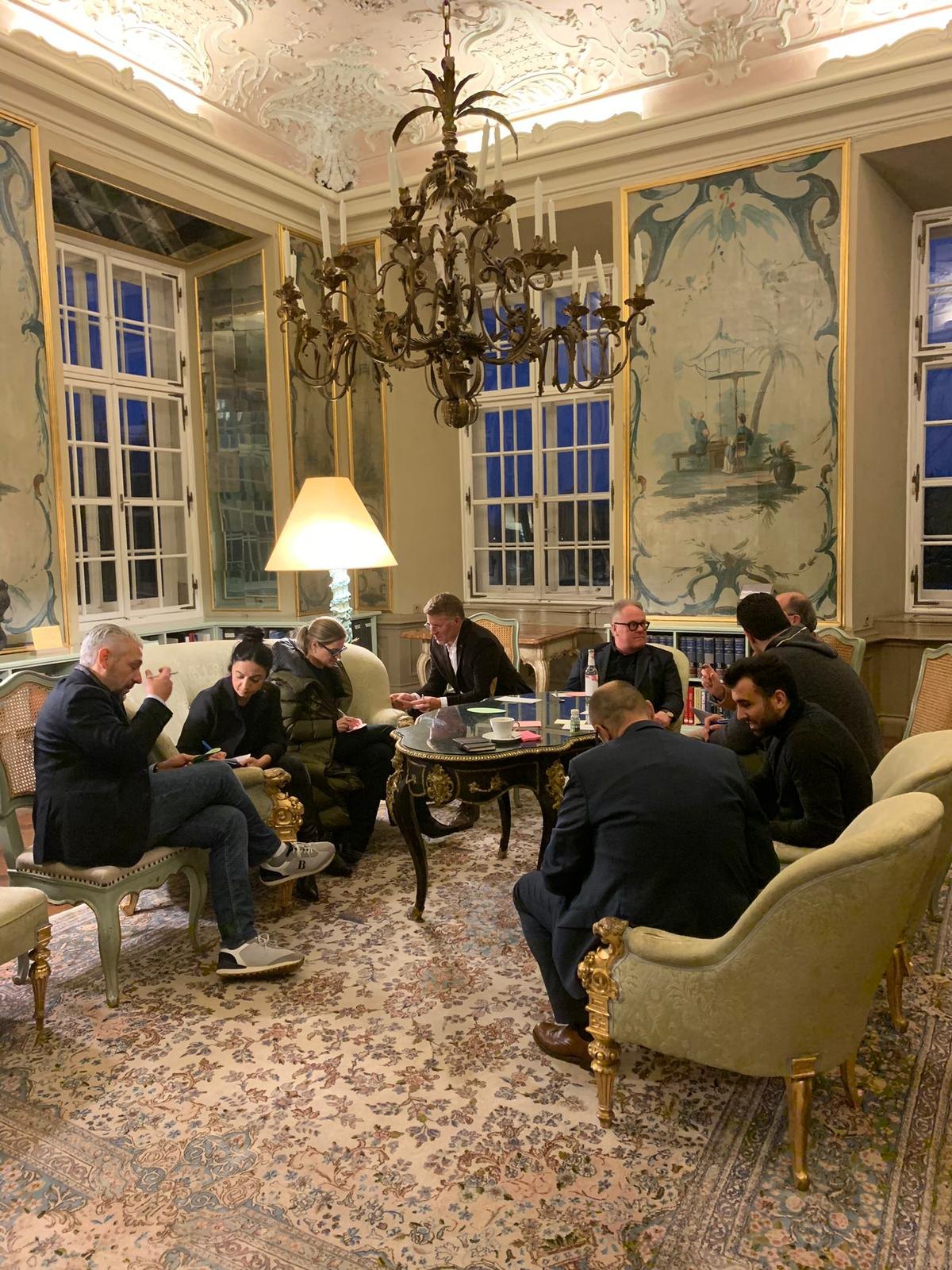 Participants gathered in a small conversation circle in an ornate room at the 2023 Sonophilia Annual Meeting.